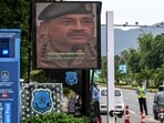 Police personnel stand guard as they inspect vehicles at a checkpost beside a large screen displaying Pakistan's army chief, Field Marshal Syed Asim Munir, in the Red Zone area in Islamabad earlier this year. 