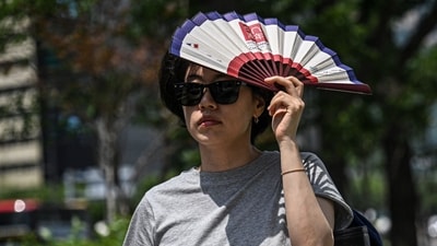 A woman uses a fan to shelter from the sun on a street in Seoul on July 12, 2026. (AFP) A woman uses a fan to shelter from the sun on a street in Seoul on July 12, 2026. (AFP)