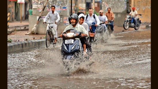 Commuters making their way through rain in Amritsar on Sunday. (Sameer Sehgal/HT)