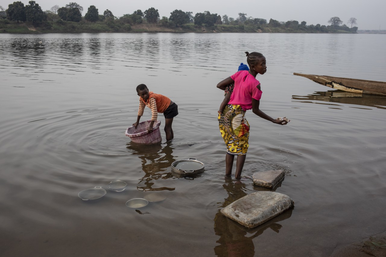 A boy washes utensils in the Oubangui River. A boy washes utensils in the Oubangui River.