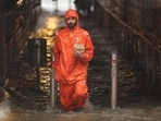 A gig worker wades through a waterlogged subway.