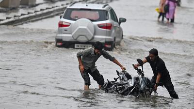 Two people struggle after their bike falls into a waterlogged stretch near Narsinghpur village on July 7 during the first official ‘heavy’ rain of the season. (Parveen Kumar/HT) Two people struggle after their bike falls into a waterlogged stretch near Narsinghpur village on July 7 during the first official ‘heavy’ rain of the season. (Parveen Kumar/HT)