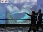 People pass by an electronic board showing areas of the disputed South China Sea during a conference to mark the 10th anniversary of a 2016 arbitration ruling which invalidated China's expansive claims during a conference in Manila, Philippines on Friday, July 10, 2026. (AP) (AP Photo/Aaron Favila)