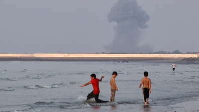 Three boys play in the shallow waters of the Strait of Hormuz, while a plume of smoke rises from an explosion in the background, off Bandar Abbas, Iran, Monday (AP) Three boys play in the shallow waters of the Strait of Hormuz, while a plume of smoke rises from an explosion in the background, off Bandar Abbas, Iran, Monday (AP)