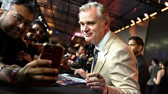 British-American filmmaker Christopher Nolan (R) poses with a fan upon his arrival to attend the red carpet for the premiere of the film 'The Odyssey' in Mumbai on July 11, 2026.