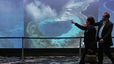 People pass by an electronic board showing areas of the disputed South China Sea during a conference to mark the 10th anniversary of a 2016 arbitration ruling which invalidated China's expansive claims during a conference in Manila, Philippines. (AP/Aaron Favila) People pass by an electronic board showing areas of the disputed South China Sea during a conference to mark the 10th anniversary of a 2016 arbitration ruling which invalidated China's expansive claims during a conference in Manila, Philippines. (AP/Aaron Favila)