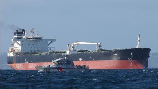 A French Navy vessel sails by the Russian oil tanker “Tagor”, suspected of flying a false Cameroonian flag and boarded by the French Navy on May 31 as it arrives in Douarnenez Bay, western France on June 2. (AFP)