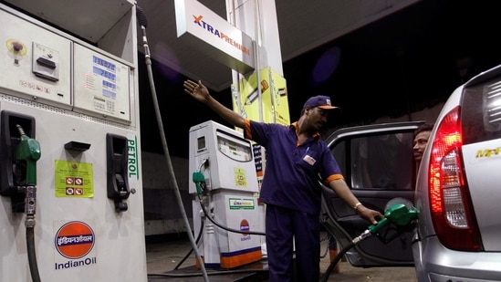 A worker fills a car with petrol as he gestures towards the fuel barometer for the passenger to check, at a fuel station in Kolkata.
