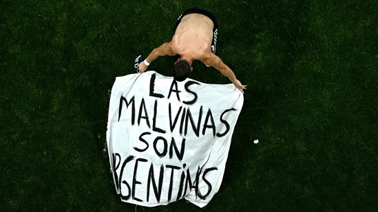 Argentina's midfielder #11 Giovani Lo Celso adjusts a banner reading "The Malvinas (Falkland Islands) belong to Argentina," after winning the 2026 World Cup football tournament semi-final match between England and Argentina at the Atlanta Stadium in Atlanta on July 15.