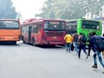 People run to catch a DTC bus at the Super Bazar bus stop at Rajiv Chowk, in New Delhi.