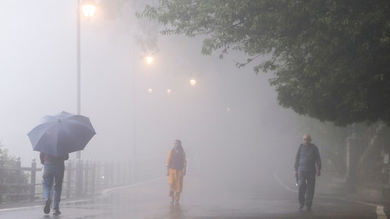 Shimla: People take a walk through dense fog on a rainy monsoon evening, in Shimla, Himachal Pradesh,.