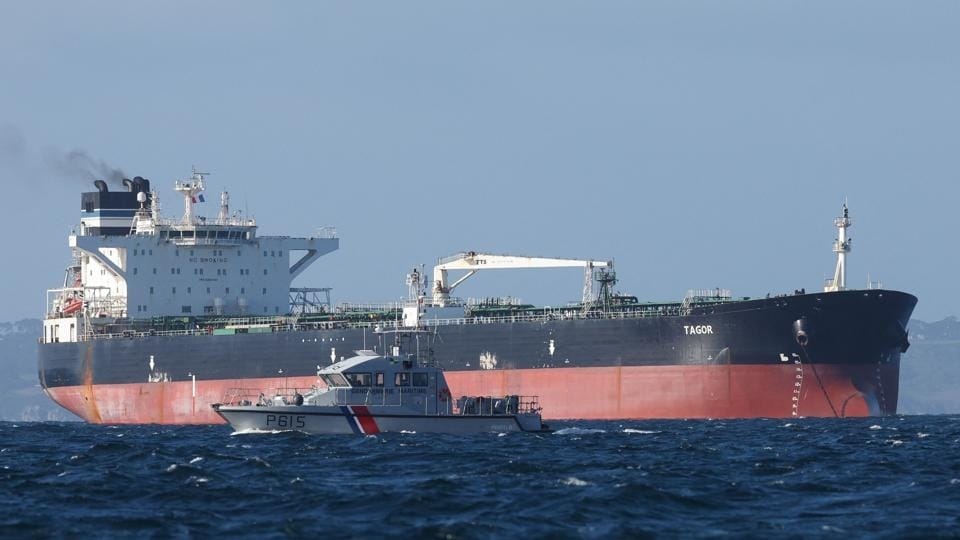 A French Navy vessel sails by the Russian oil tanker “Tagor”, suspected of flying a false Cameroonian flag and boarded by the French Navy on May 31 as it arrives in Douarnenez Bay, western France on June 2. (AFP) (HT_PRINT)