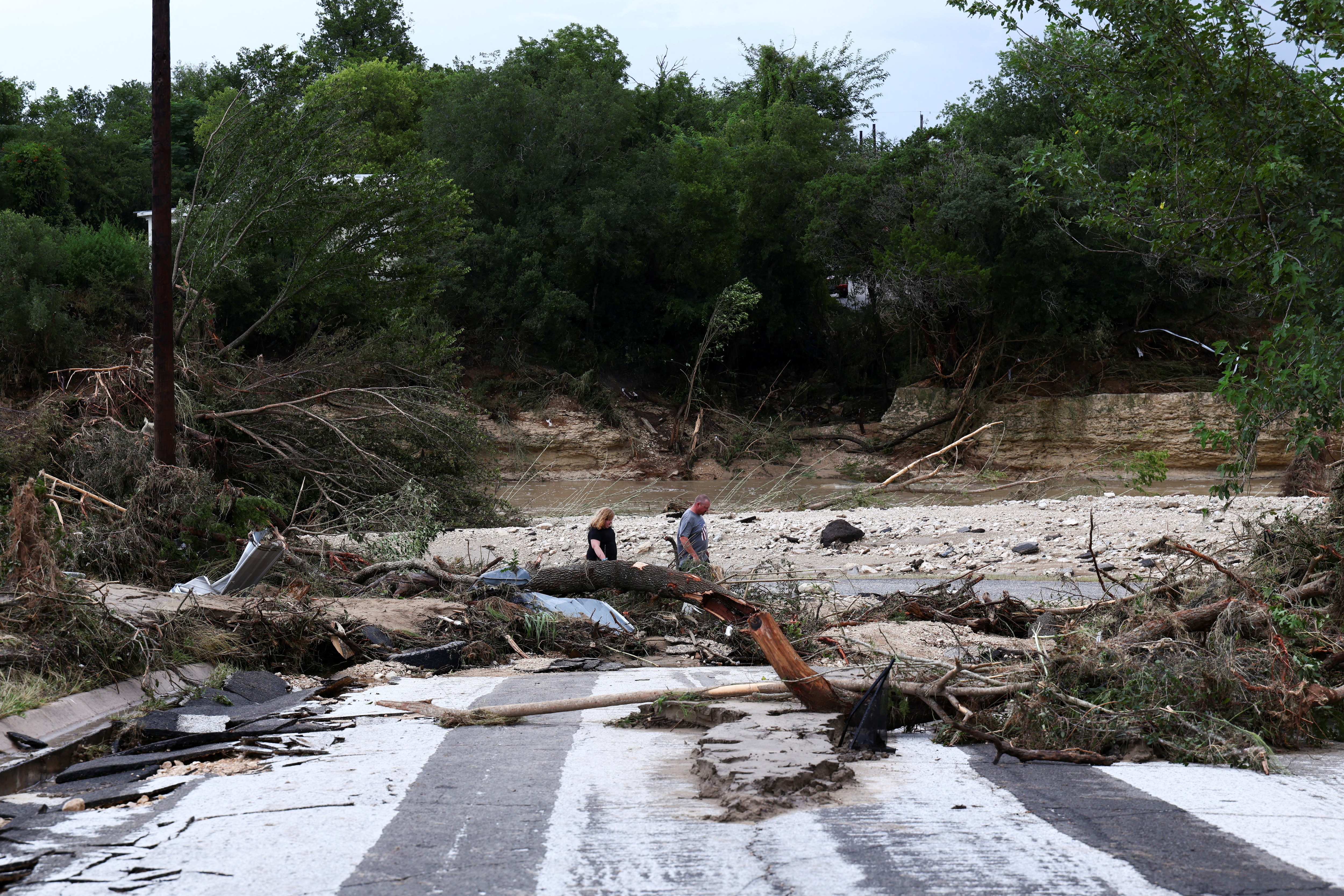 People walk through the rubble near Town Creek as heavy rains and severe weather hit southern Texas (Reuters)