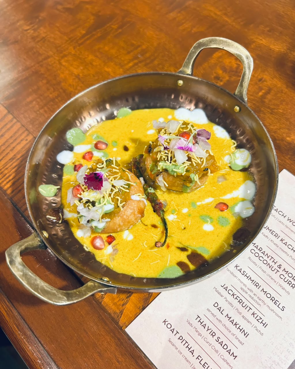 A beautiful 'mess' that makes perfect sense. Crispy Ajmeri kachori served over a vibrant bed of kadhi, khatta-meetha pumpkin, chutneys, and pomegranate seeds. (Pic: Sanya Panwar) A beautiful 'mess' that makes perfect sense. Crispy Ajmeri kachori served over a vibrant bed of kadhi, khatta-meetha pumpkin, chutneys, and pomegranate seeds. (Pic: Sanya Panwar)