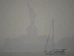 The Statue of Liberty is hardly visible as smoke from wildfires blankets the sky, (AP)