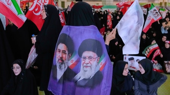 A mourner wears a banner showing portraits of the late Iranian Supreme Leader Ayatollah Ali Khamenei, right, and his son Ayatollah Mojtaba Khamenei, the successor to him, in a ceremony commemorating the late leader at the Imam Khomeini Mosalla Grand Mosque in Tehran, Tuesday, July 14, 2026. A mourner wears a banner showing portraits of the late Iranian Supreme Leader Ayatollah Ali Khamenei, right, and his son Ayatollah Mojtaba Khamenei, the successor to him, in a ceremony commemorating the late leader at the Imam Khomeini Mosalla Grand Mosque in Tehran, Tuesday, July 14, 2026.