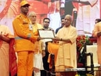 Chief minister Yogi Adityanath honoured eight personnel of the NDRF, SDRF, PAC and fire services for displaying exceptional courage during disaster response operations. (HT)