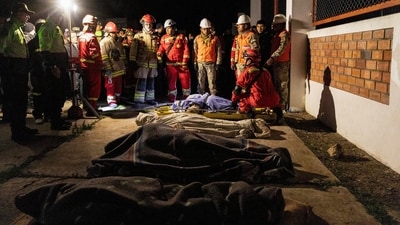 People pray next to the bodies of four victims of the earthquake of magnitude 5.6 that struck Central Peru on Saturday. (REUTERS)