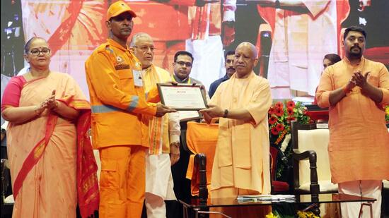 Chief minister Yogi Adityanath honoured eight personnel of the NDRF, SDRF, PAC and fire services for displaying exceptional courage during disaster response operations. (HT)