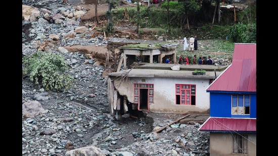 People stand near a house damaged due to a flash flood, in Poonch. (REUTERS)