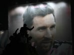 Argentina's fans are silhouetted as they stand atop a structure with an image of Lionel Messi in the background near the Obelisk after Argentina lost the FIFA World Cup final