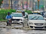 Commuters make their way through a waterlogged road in Ludhiana following heavy rain on Sunday. (Gurpreet Singh/HT)