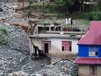 People stand near a house damaged due to a flash flood, in Poonch. (REUTERS)