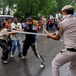 A policeman wields his baton against demonstrators following a clash during a march by supporters of Cockroach Janta Party towards Parliament on the opening day of its Monsoon Session, demanding the resignation of education minister Dharmendra Pradhan over exam paper leaks, near Jantar Mantar in New Delhi on July 20, 2026.