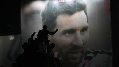 Argentina's fans are silhouetted as they stand atop a structure with an image of Lionel Messi in the background near the Obelisk after Argentina lost the FIFA World Cup final (AFP)