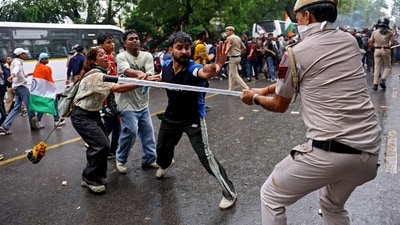 A policeman holds a baton against protesters after a clash during a march by supporters of the Janta Party towards Parliament on the opening day of the monsoon session, demanding the resignation of Education Minister Dharmendra Pradhan over exam paper leaks, near Jantar Mantar in New Delhi, July 20, 2026. (Anushree Fadnavis/Reuters)
