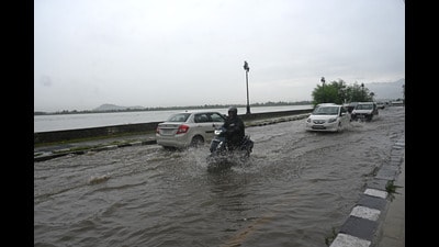 People travelling through a waterlogged road during heavy rainfall in Srinagar. (Waseem Andrabi/HT)