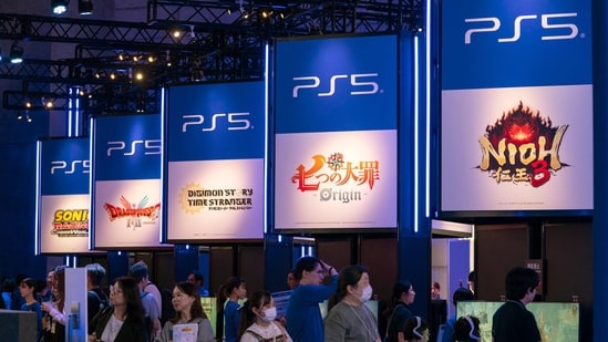 Visitors walk in front of the booth for Sony's PlayStation.