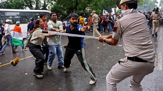 A policeman wields his baton against demonstrators following a clash during a march by supporters of Cockroach Janta Party towards Parliament on the opening day of its Monsoon Session, demanding the resignation of education minister Dharmendra Pradhan over exam paper leaks, near Jantar Mantar in New Delhi on July 20, 2026.
