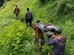 Mountaineering rescue team members carry an injured person on a stretcher along the trails of the Bada Bhangal, in Kangra on Monday. (PTI)