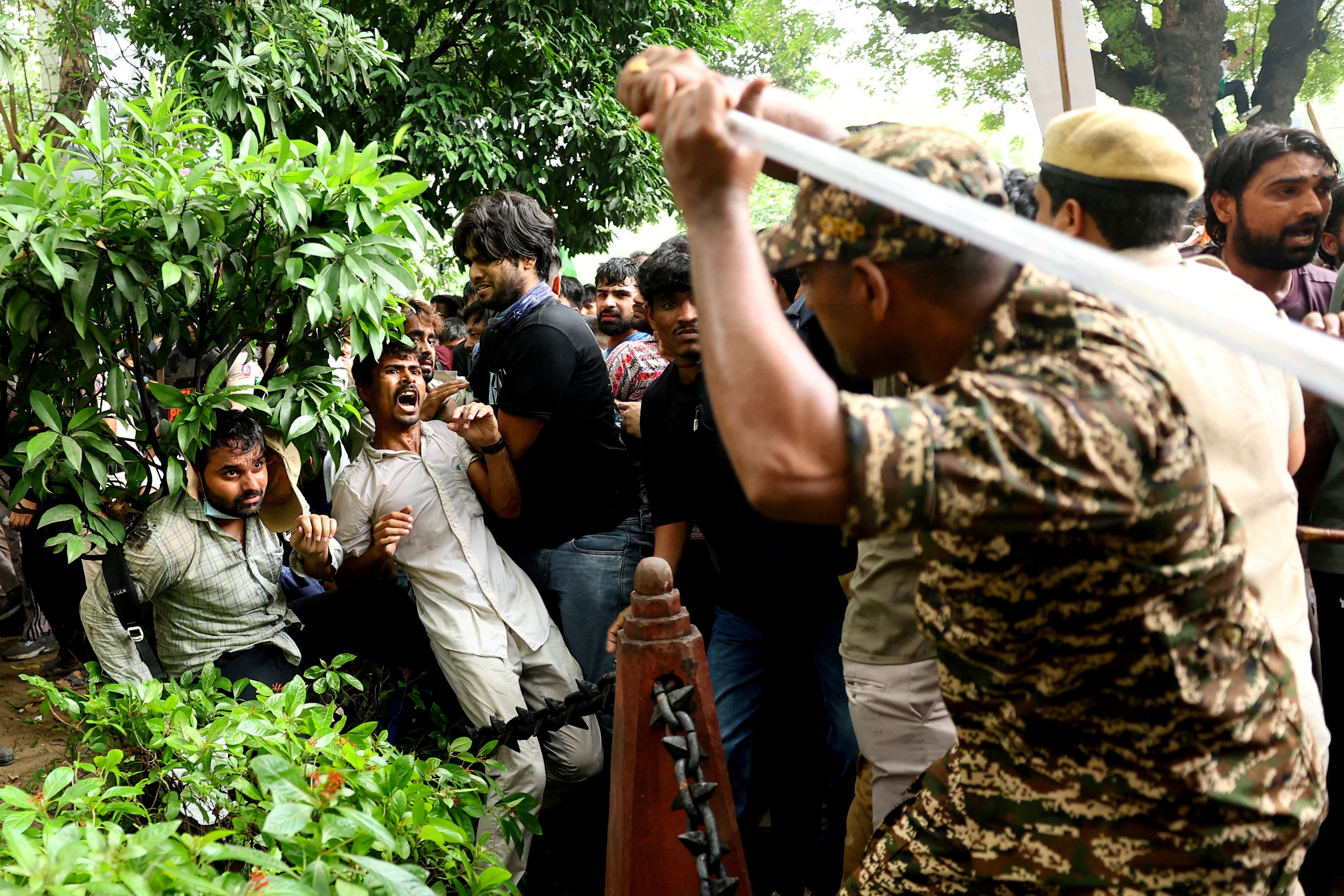 A security force personnel wields his baton against demonstrators at a protest site during a planned march by supporters of India's Cockroach Janta Party towards parliament on the opening day of its monsoon session. (REUTERS)