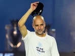 Pep Guardiola raises his hat to the crowd during a stage event.