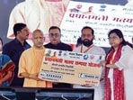 Chief minister Yogi Adityanath presents cheque to a beneficiary during the inauguration and foundation stone-laying of 70 development projects worth over  <span class='webrupee'>₹</span>352 crore in the Mahsi and Nanpara Assembly constituencies, in Bahraich on Tuesday. (@myogiadityanath X/ANI Photo)