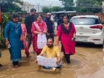 Residents stand in stagnant water, holding placards to protest civic neglect. (Sourced)
