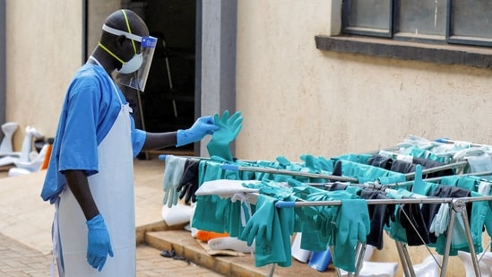 A Ugandan worker collects a rubber glove from the airing line during a visit by the Director-General of the World Health Organisation (WHO) Tedros Adhanom Ghebreyesus at the Mulago National Referral Hospital Isolation Unit.
