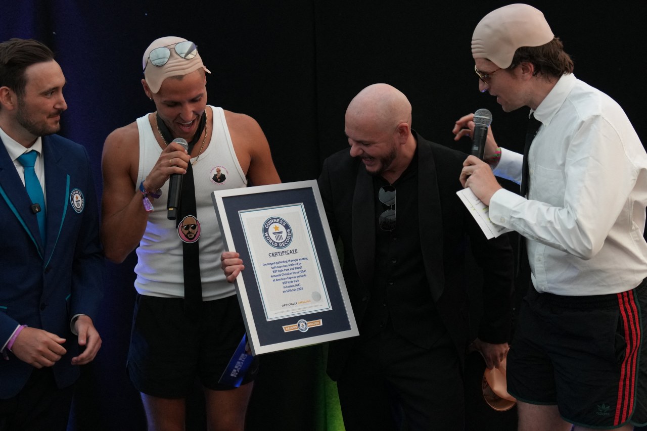 Pitbull receives a certificate from Guinness World Records for achieving the largest number of people sporting bald caps.