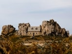 Squeezed between two giant rocks in France, this 160-year-old cottage was built to survive wild ocean storms. (Unsplash)