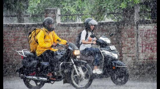 Commuters cover themselves as they make their way amid heavy rainfall, in Prayagraj on Thursday. (ANI Photo)