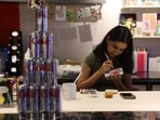 A woman uses rhinestones to decorate a Diet Coke can for an upcoming party to attract fans of the beverage amid an aluminium can shortage caused by disruption from the US and Israel's war with Iran, inside a cafe in New Delhi.