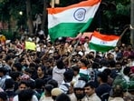 CJP supporters wave the national flag during a protest demanding the resignation of Pradhan over NEET paper leak issue. 