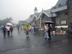 People cover themselves with umbrellas amid rainfall, in Shimla on Thursday. (ANI)