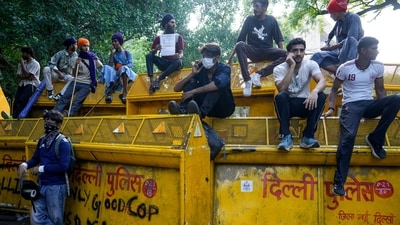 Supporters of the Cockroach Janta Party (CJP) sit on barricades during a protest demanding the resignation of Education Minister Dharmendra Pradhan over the NEET papers leak issue. (PTI)