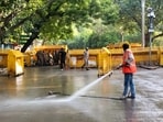 An NDMC worker washes the road during a cleanliness drive at the protest site of Jantar Mantar, in New Delhi on Saturday.