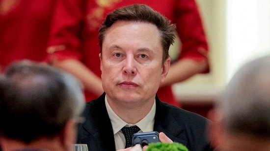 FILE PHOTO: Tesla CEO Elon Musk holds a mobile phone as he arrives to attend a state banquet with U.S. President Donald Trump and Chinese President Xi Jinping at the Great Hall of the People in Beijing, China, May 14, 2026. REUTERS/Evan Vucci/File Photo