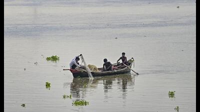 Fishermen try to catch fish from the Ganga river as the water level rises in Prayagraj on Monday (PTI)