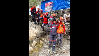 Personnel of the Jammu and Kashmir Police (JKP) Mountain Rescue Team (MRT) carry a pilgrim on a stretcher while providing assistance along the Baltal route during the annual Amarnath Yatra, on Monday. (PTI)